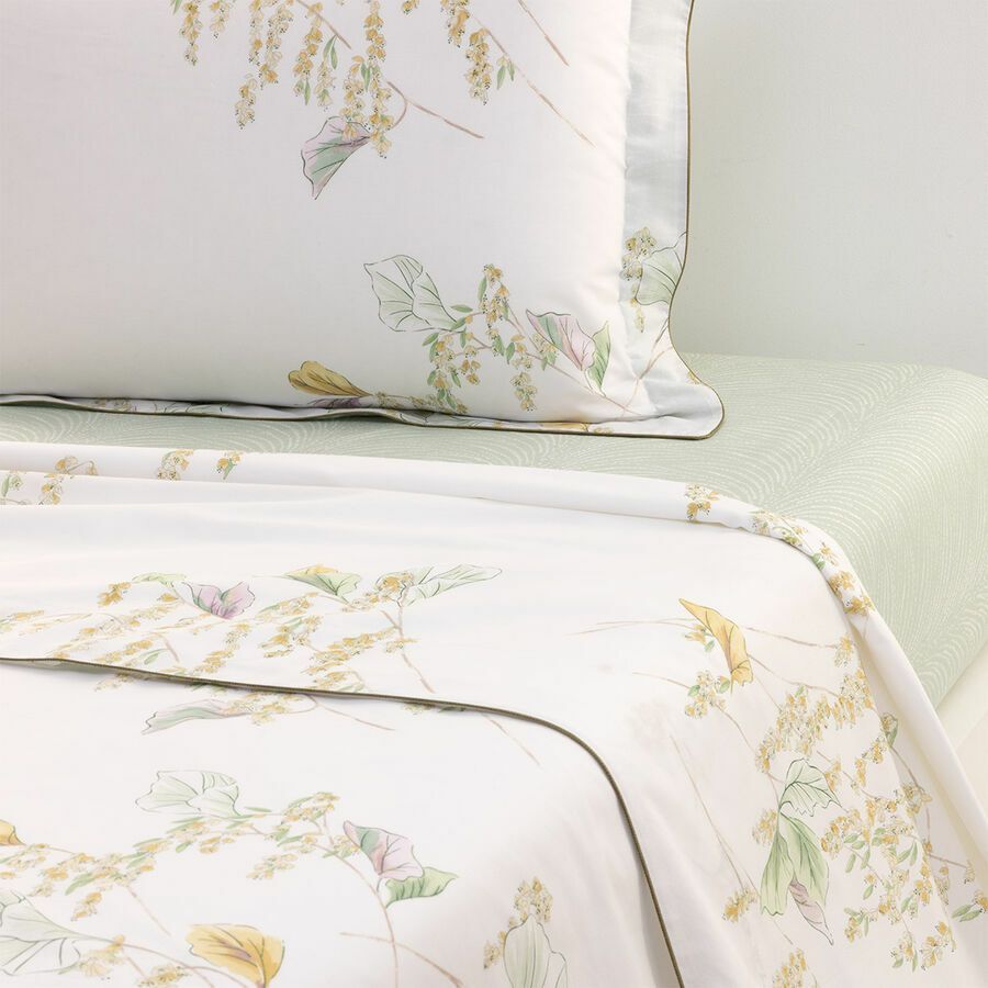 Draps blancs à motifs floraux avec un drap vert en dessous.