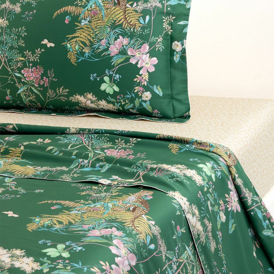 Draps et oreiller à motifs floraux verts sur un lit.