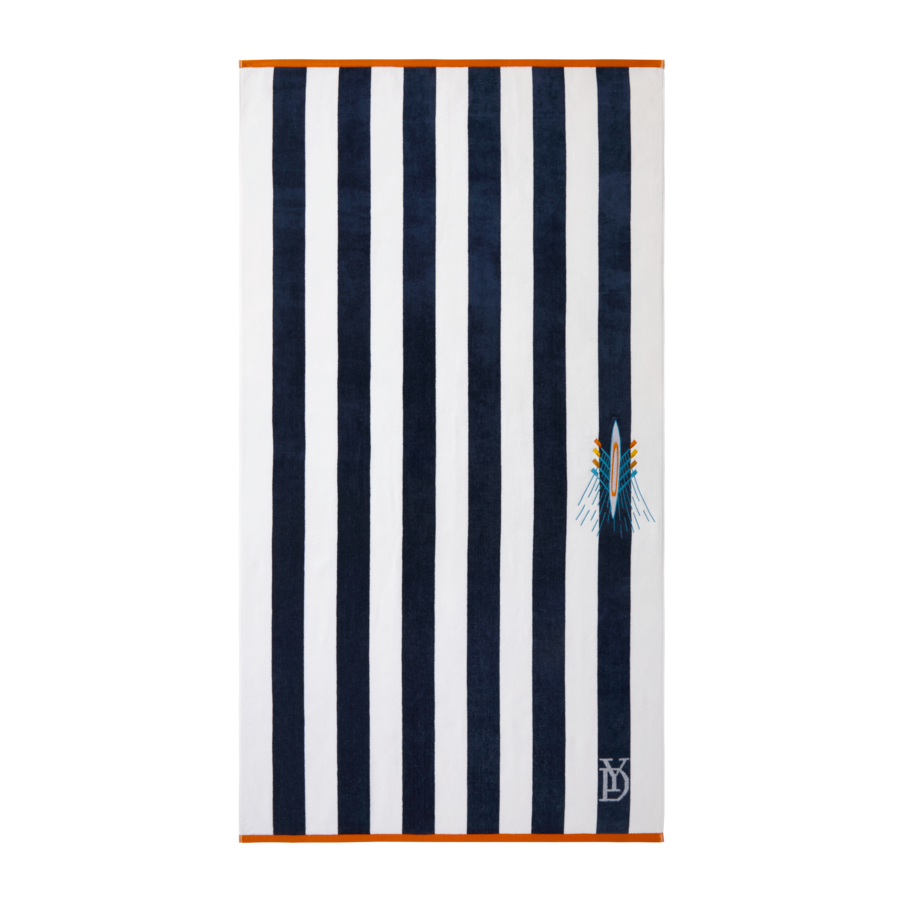 Serviette de plage à rayures bleu marine et blanches avec une bordure orange, un petit emblème brodé et un logo monogramme en bas.