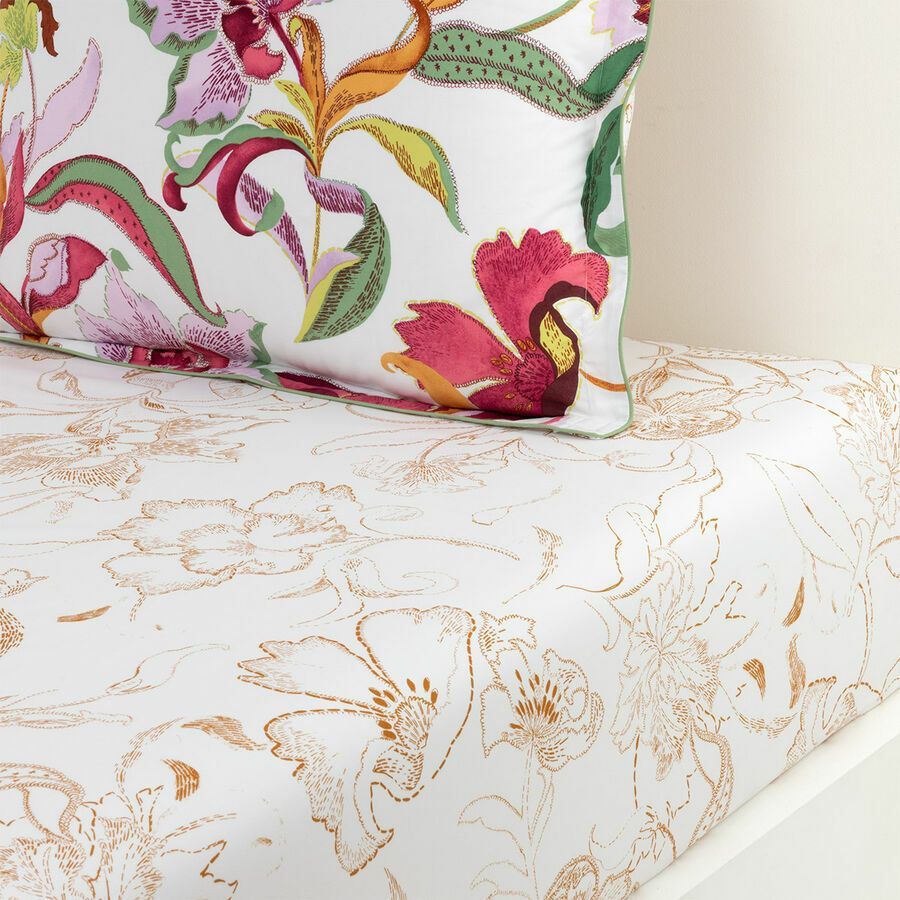 Un oreiller sur un lit avec un motif floral dessus