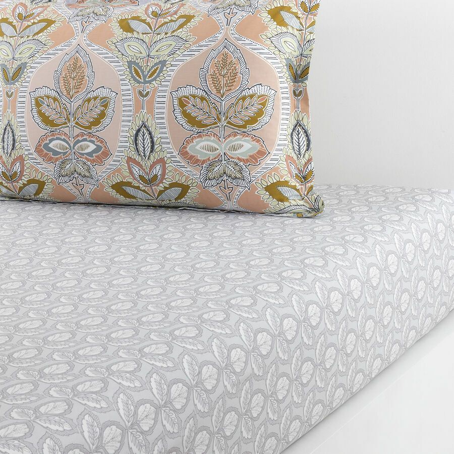 Ensemble de literie : oreiller à motifs sur drap-housse gris clair.