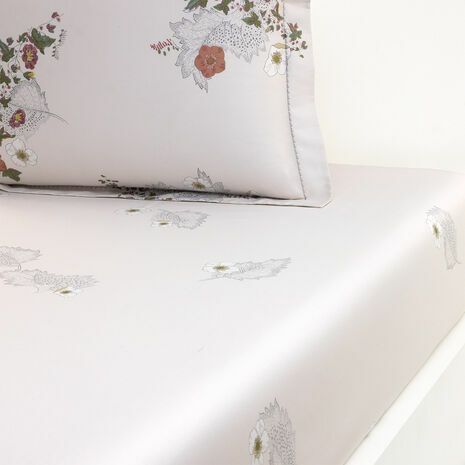 Linge de lit à motifs floraux dans les tons de blanc, gris et rouille.