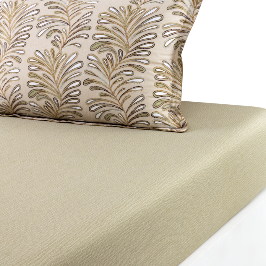 Un drap-housse texturé beige clair avec un coussin décoratif beige orné d'un motif de feuilles métalliques répétitif.