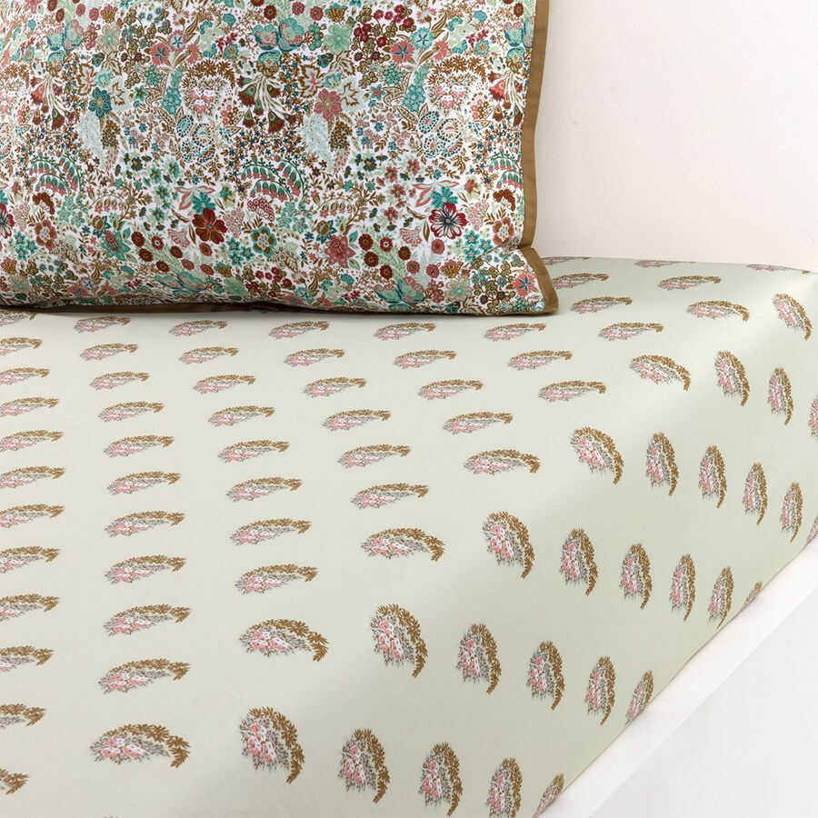 Un lit avec un oreiller fleuri et un drap cachemire