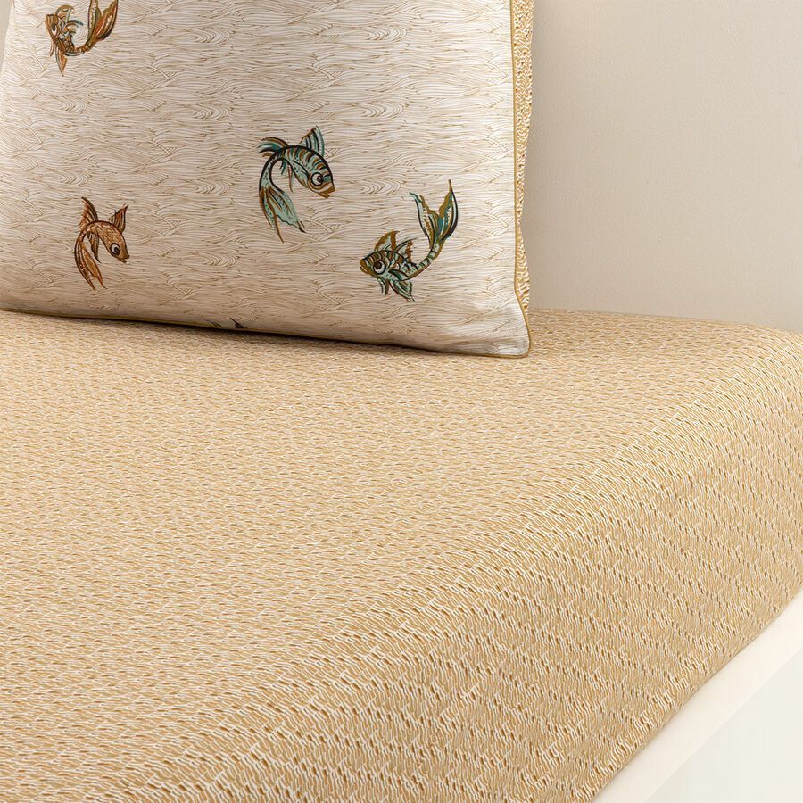 Un oreiller avec un poisson dessus est posé sur un lit.