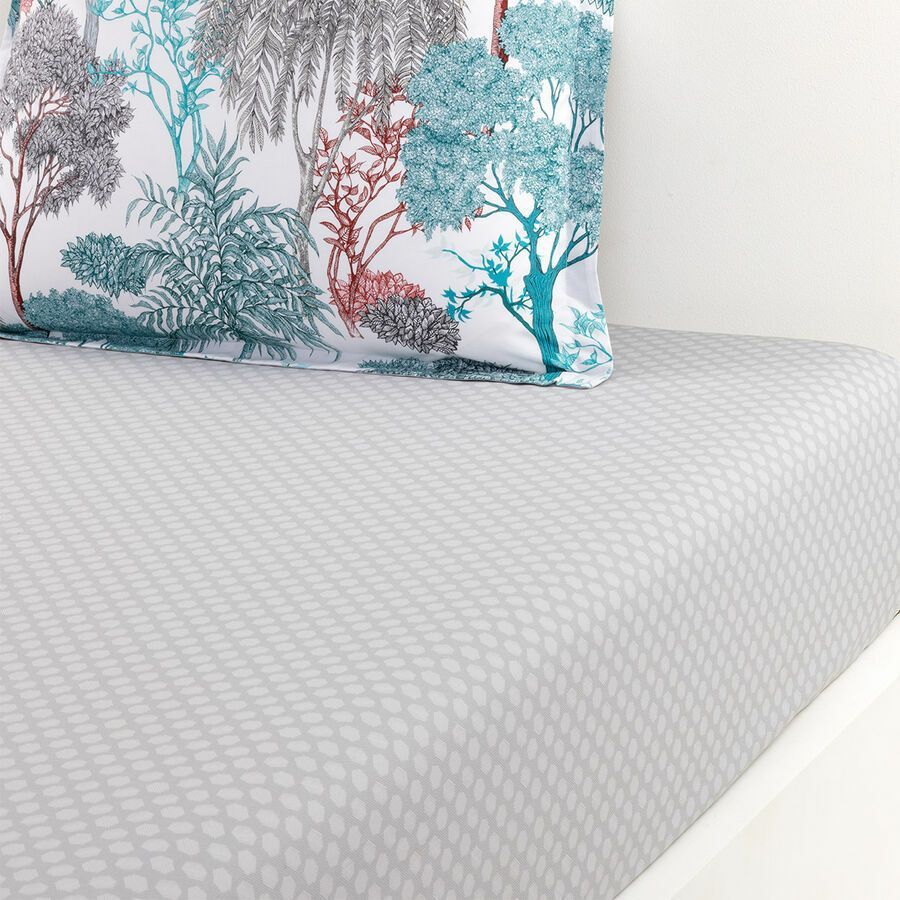 Un lit avec un oreiller avec des arbres dessus