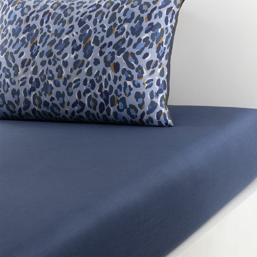 Drap-housse bleu marine et oreiller à motifs sur un lit.