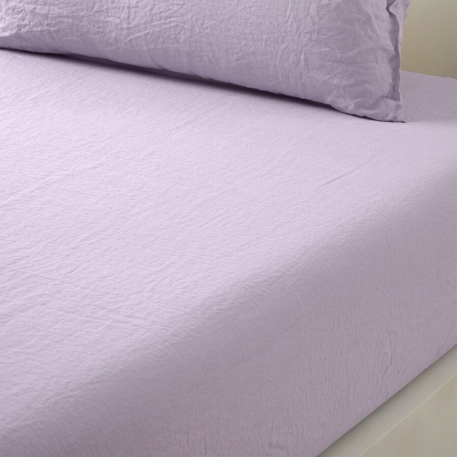 Un gros plan d'un couvre-lit violet et d'un oreiller sur un lit.