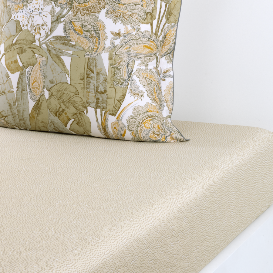 Un oreiller avec un motif floral est posé sur un lit