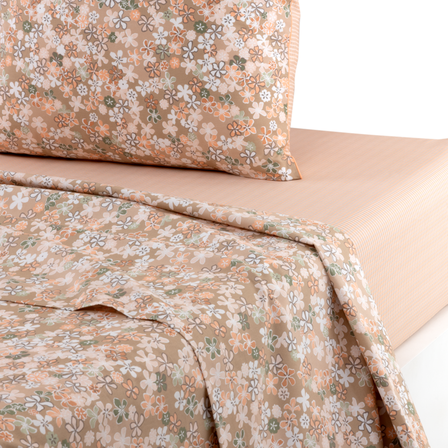 Draps beiges à petits motifs floraux, assortis à une taie d'oreiller, sur un sommier à rayures douces.