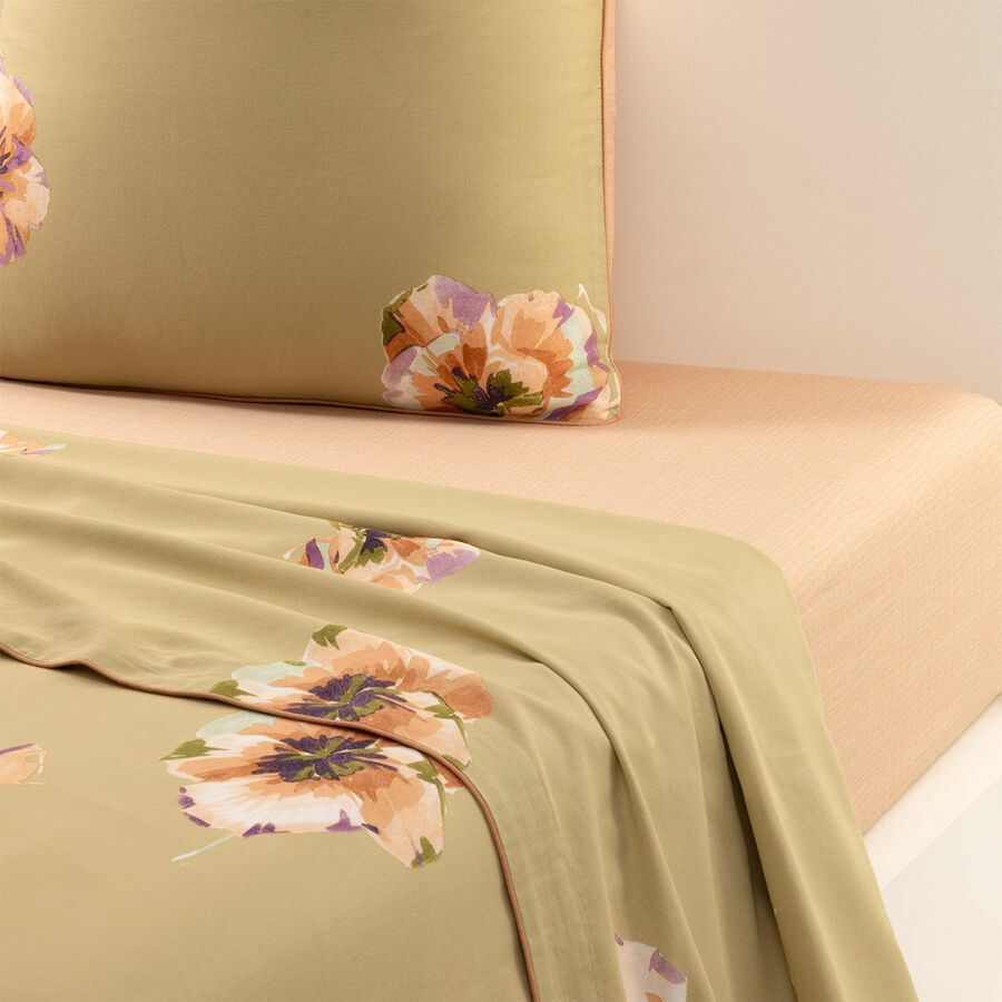 Un lit avec une couette fleurie et des oreillers dessus