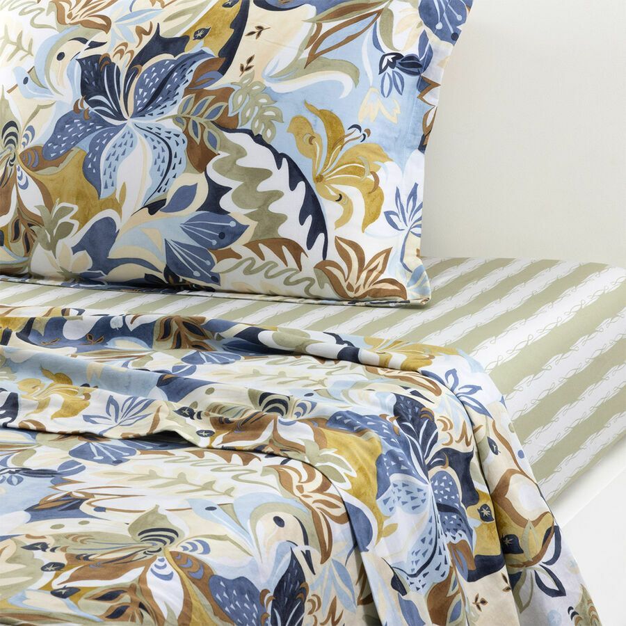 Linge de lit à motifs floraux dans les tons bleus, beiges et blancs, avec draps rayés.