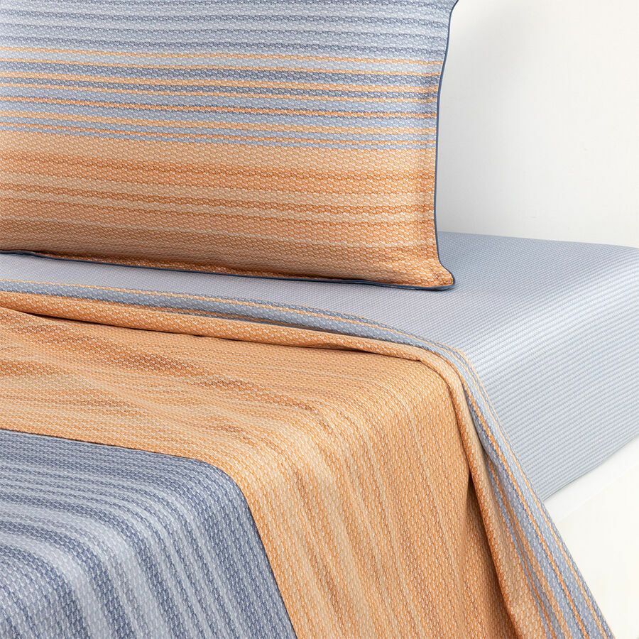 Un lit avec une couette rayée et des oreillers dessus