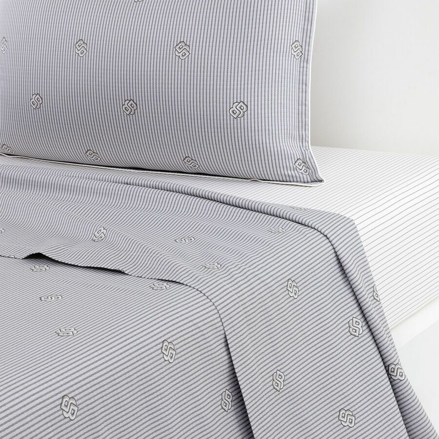 Draps de lit gris à rayures et taie d'oreiller assortie ornée d'un petit motif circulaire blanc brodé.