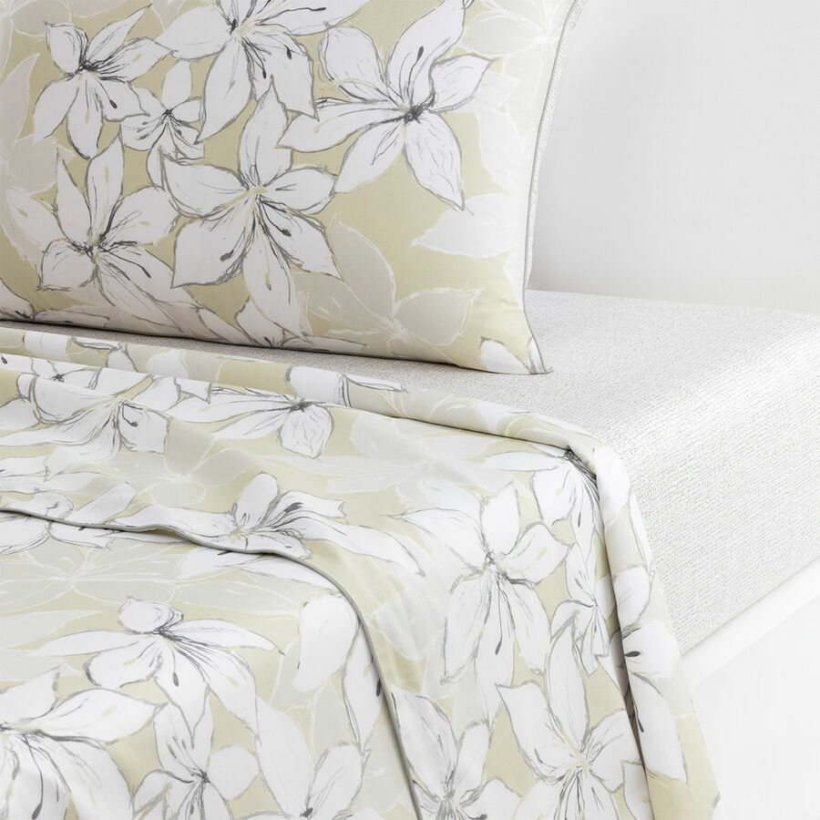 Un lit avec une couette fleurie et des oreillers dessus