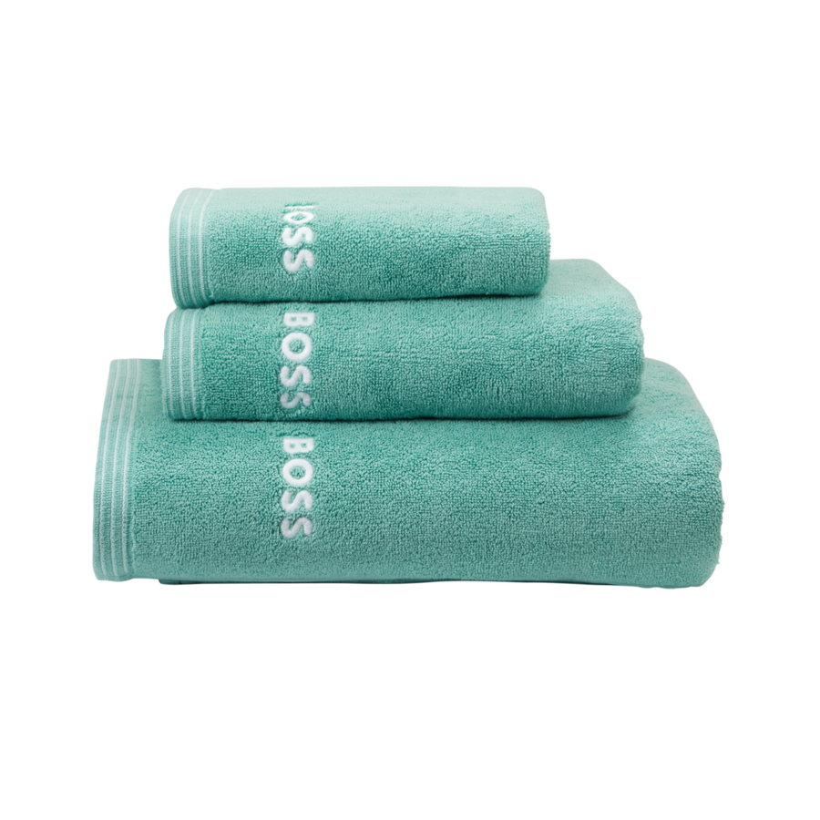 Trois serviettes de bain turquoise empilées, de tailles différentes, chacune arborant le logo blanc « BOSS » sur le côté.