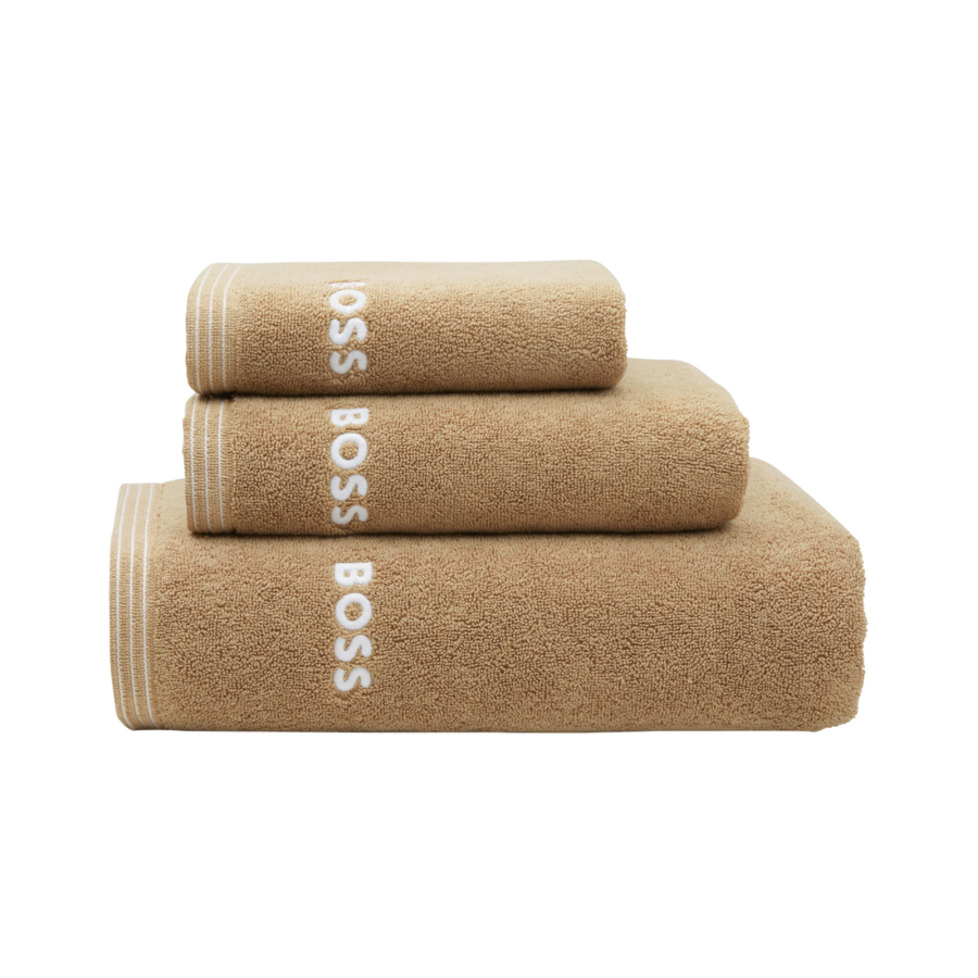 Trois serviettes beiges soigneusement empilées, chacune ornée du logo BOSS blanc et d'une bordure rayée sur le côté gauche.