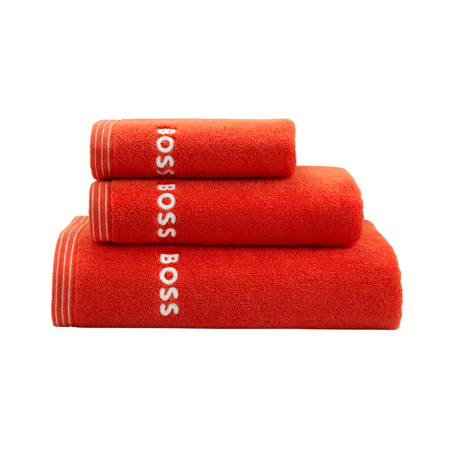 Trois serviettes de bain orange vif de tailles décroissantes sont soigneusement empilées, chacune arborant le logo BOSS en blanc.