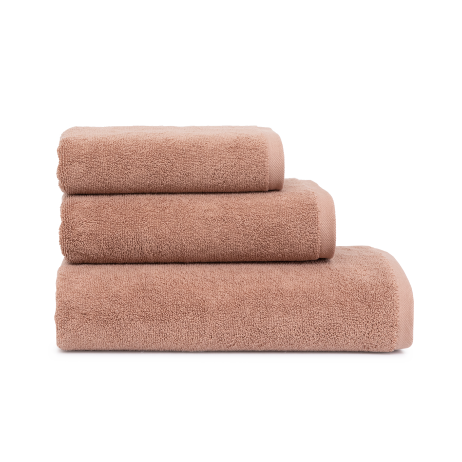 Trois serviettes roses sont empilées les unes sur les autres sur un fond blanc.