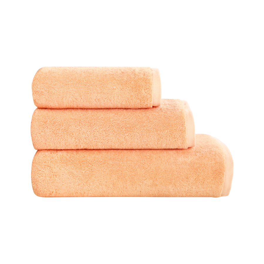 Trois serviettes couleur pêche empilées sur fond blanc.