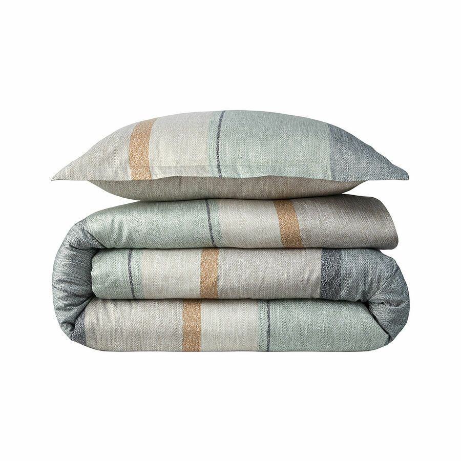 Une couette rayée et des oreillers sont empilés les uns sur les autres