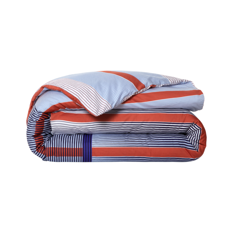 Une couette rayée bleue et rouge est enroulée sur un fond blanc.
