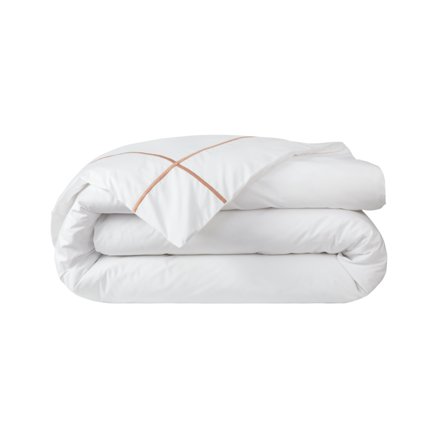 Une couette blanche avec une broderie en cuivre est empilée les unes sur les autres.