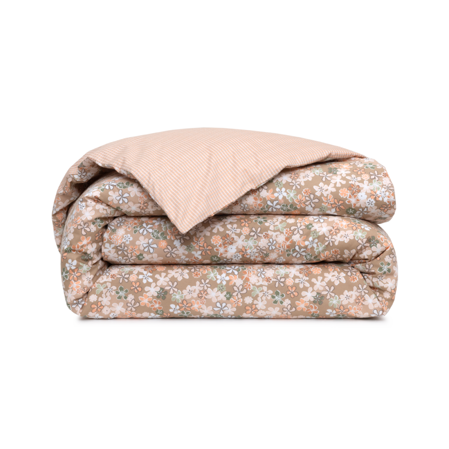 Une housse de couette pliée, à imprimé floral beige sur une face et à pois rose clair sur l'autre.