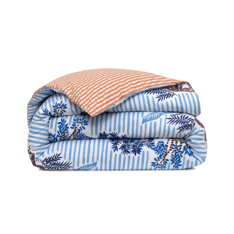 Une housse de couette pliée ornée d'un motif botanique à rayures bleues et blanches et d'un revers texturé couleur pêche.