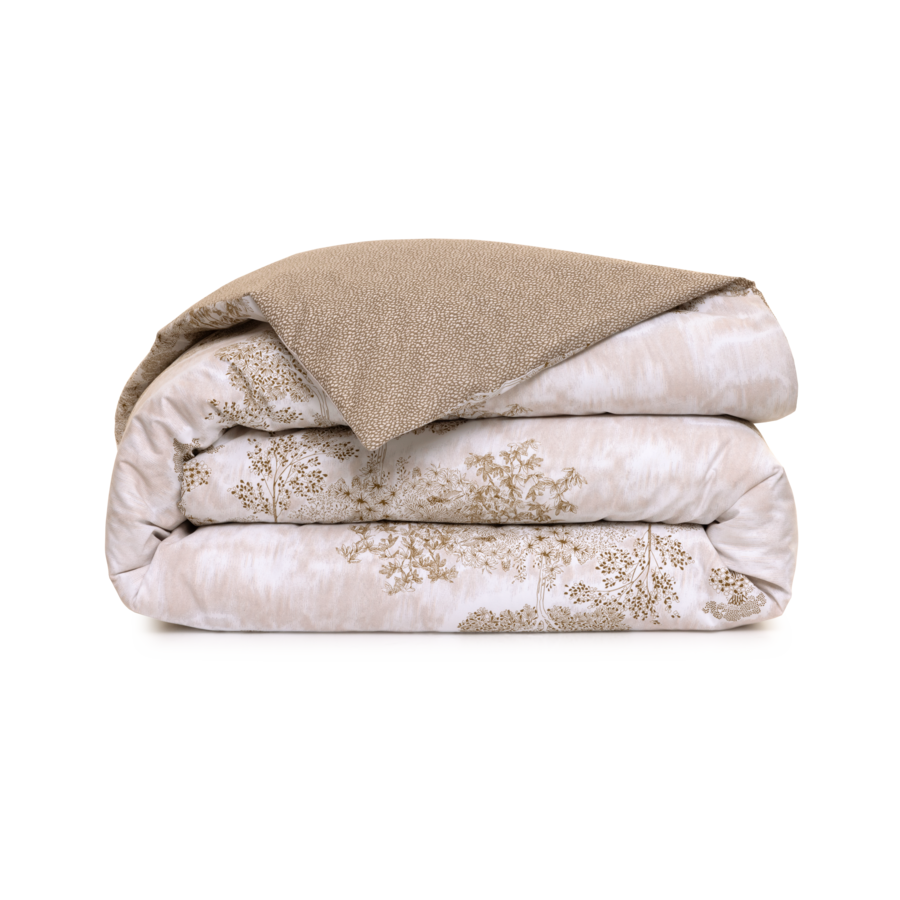 Couette pliée à motifs beiges et blancs avec un dessus marron clair.