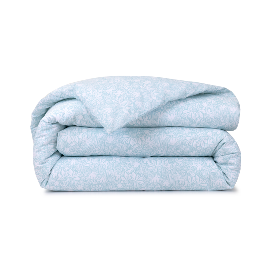 Une couette bleu clair pliée, à motifs floraux blancs sur fond blanc.