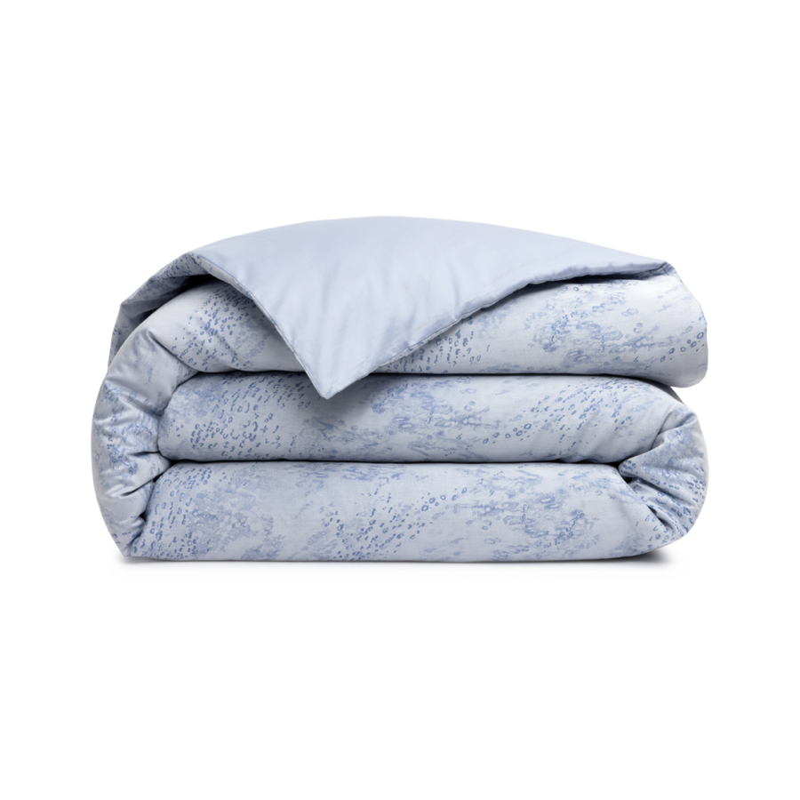 Une couette bleu clair soigneusement pliée, avec un discret motif bleu foncé imprimé sur le dessus et le dessous.