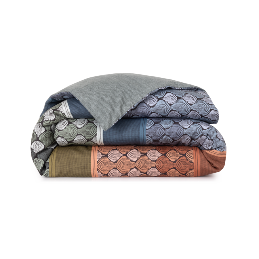 Une couverture avec un motif dessus est empilée les unes sur les autres sur un fond blanc.