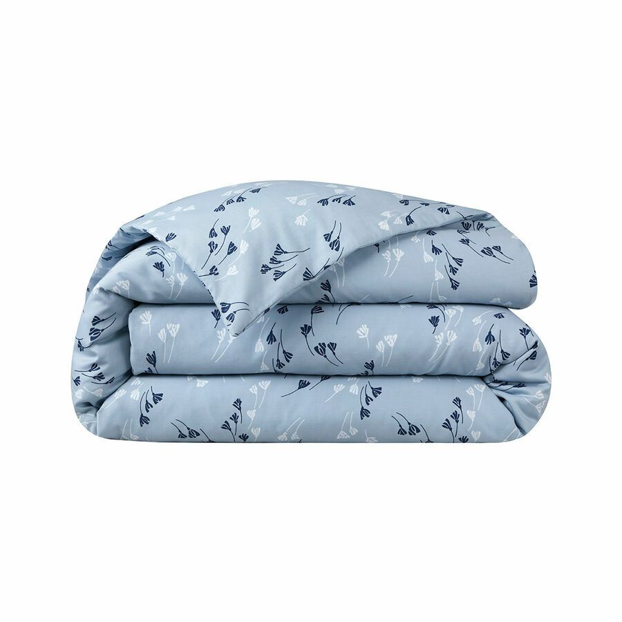 Une housse de couette bleu clair pliée, ornée d'un motif de petites formes abstraites ressemblant à des fleurs, bleu foncé et blanches.