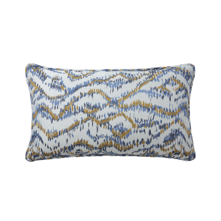 Un coussin décoratif rectangulaire à fond blanc orné de motifs horizontaux abstraits et ondulés, dans les tons bleus et jaune ocre.