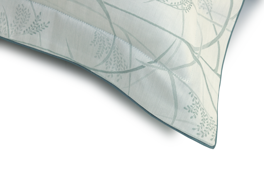 Coussin blanc à motif floral bleu pâle, bordé d'un liseré bleu foncé.