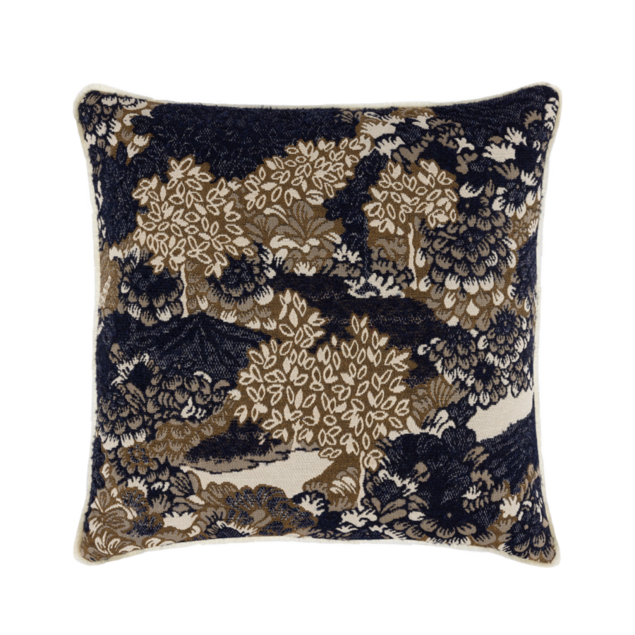 Coussin carré à motif forêt dans les tons marine, beige et marron, avec passepoil blanc.