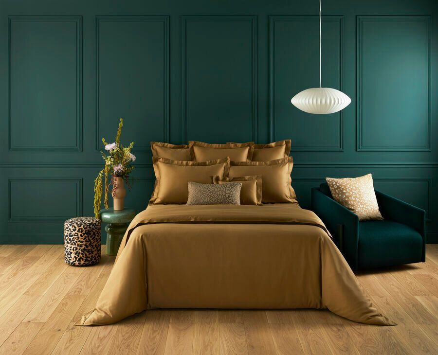 Une chambre avec un lit, une chaise, un pouf et des murs verts.