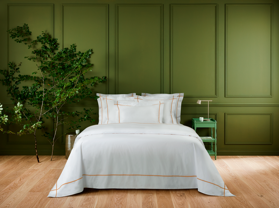 Un lit avec une couette et des oreillers blancs dans une chambre aux murs verts.