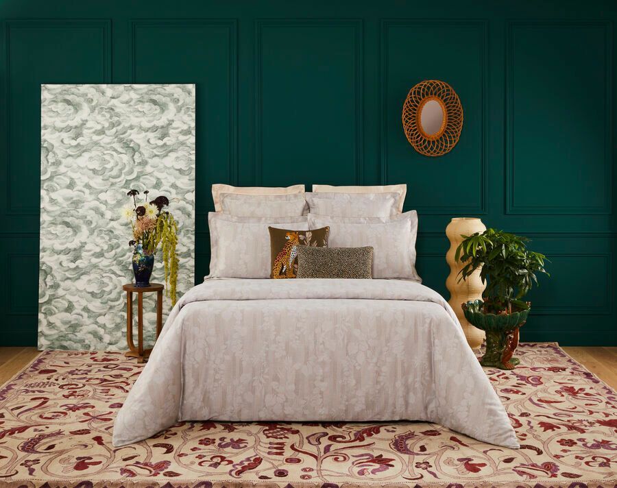 Un lit avec une couette blanche et des oreillers dans une pièce avec un mur vert.