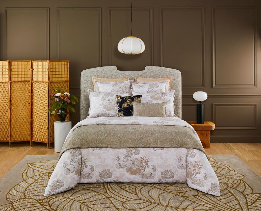 Chambre avec lit orné, touches dorées et tapis à motifs.