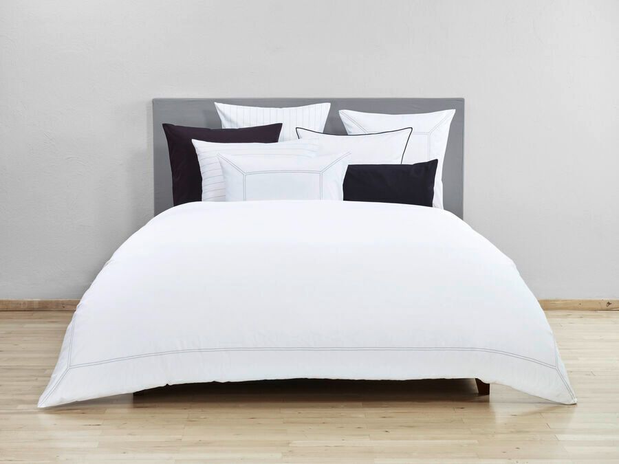 Un lit avec des draps blancs et des oreillers noirs dessus