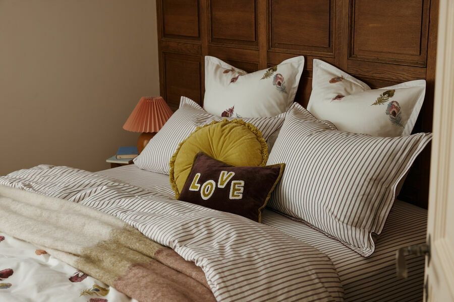 Lit avec oreillers, linge de lit à rayures et tête de lit en bois marron.