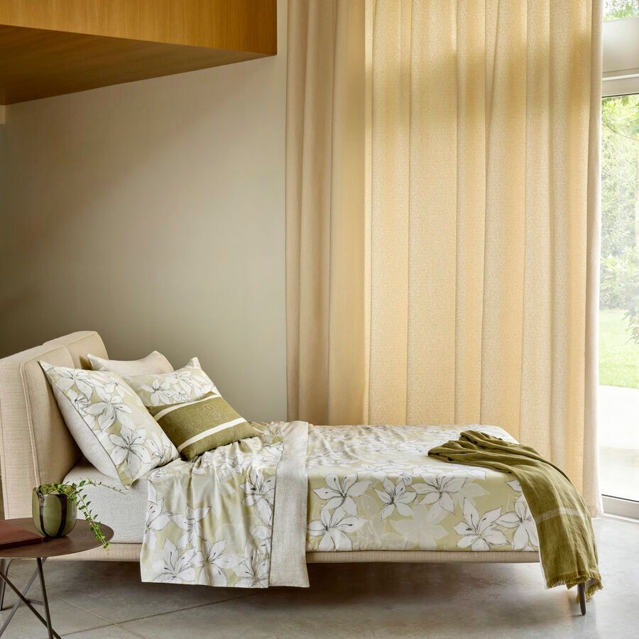 Un lit avec une couette et des oreillers à motifs floraux dans une chambre