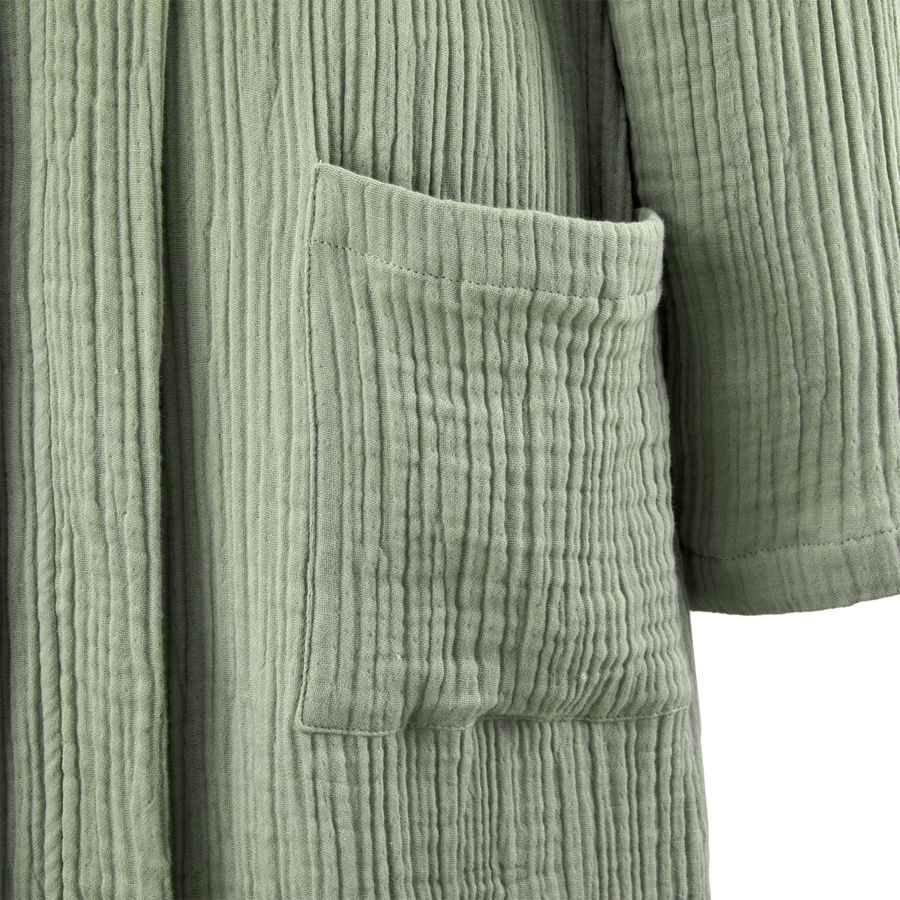 Gros plan sur une robe vert sauge en coton texturé et froissé, avec une poche plaquée.