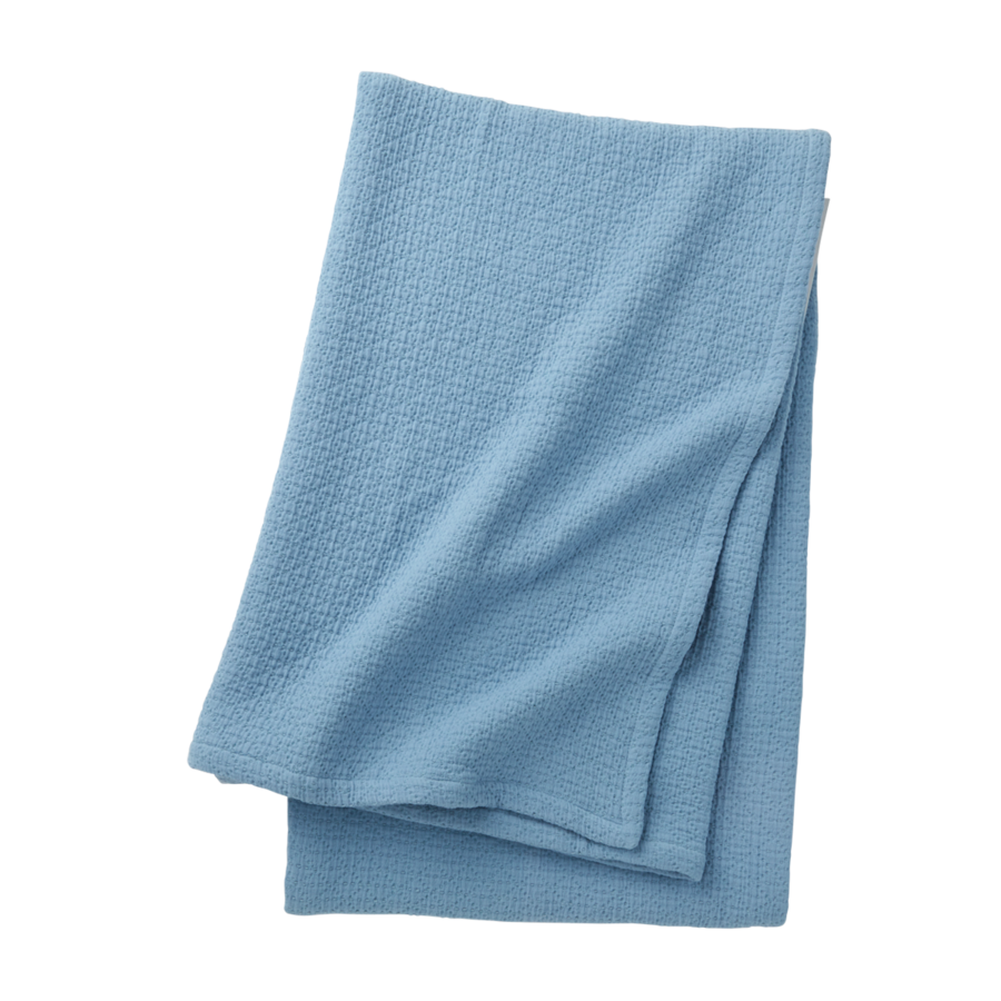 Une couverture polaire bleu clair unie, pliée, sur un fond blanc uni.