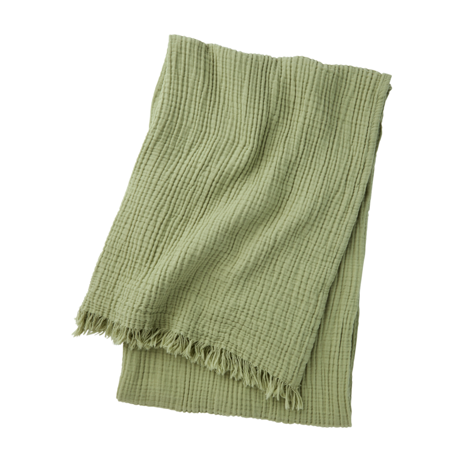 Un plaid plié en maille gaufrée vert sauge, avec des franges aux extrémités, sur fond blanc.