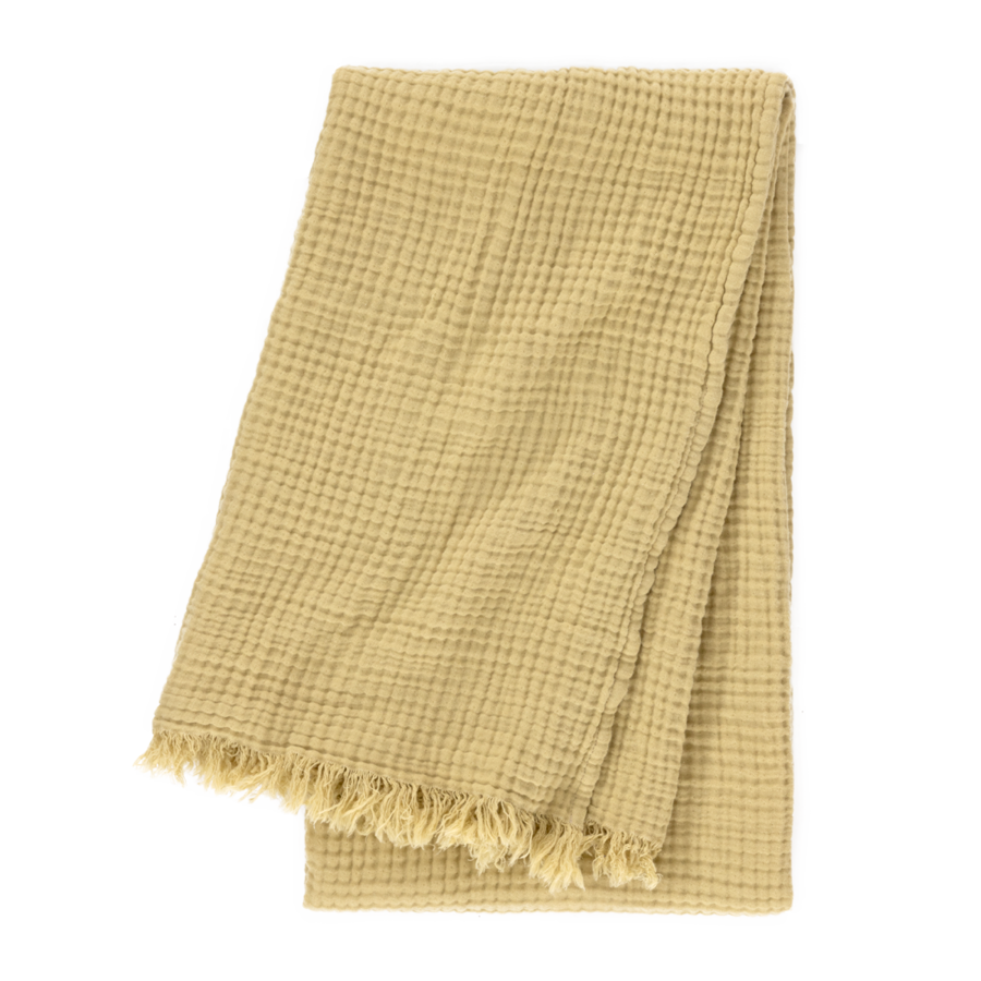 Un plaid beige en maille gaufrée, aux bords effilochés, plié et isolé sur un fond blanc.