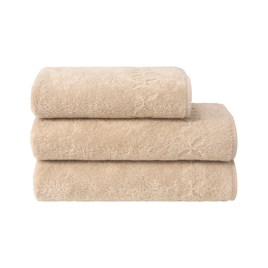 Trois serviettes de bain beiges pliées et empilées les unes sur les autres.