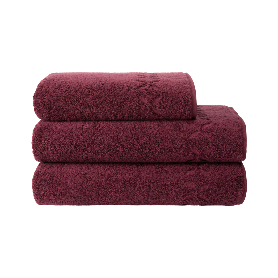 Trois serviettes de bain bordeaux empilées.